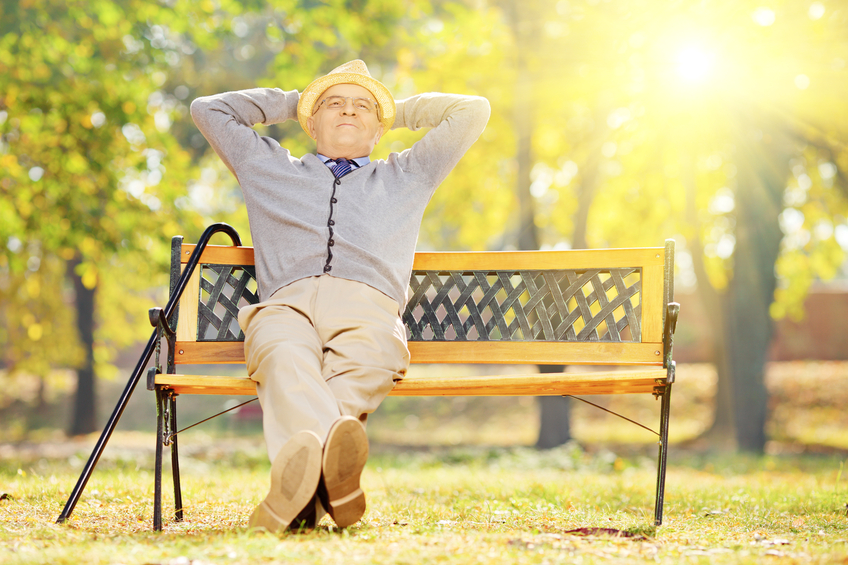 homme aîné, à, canne, séance banc, dans parc, à, coucher soleil