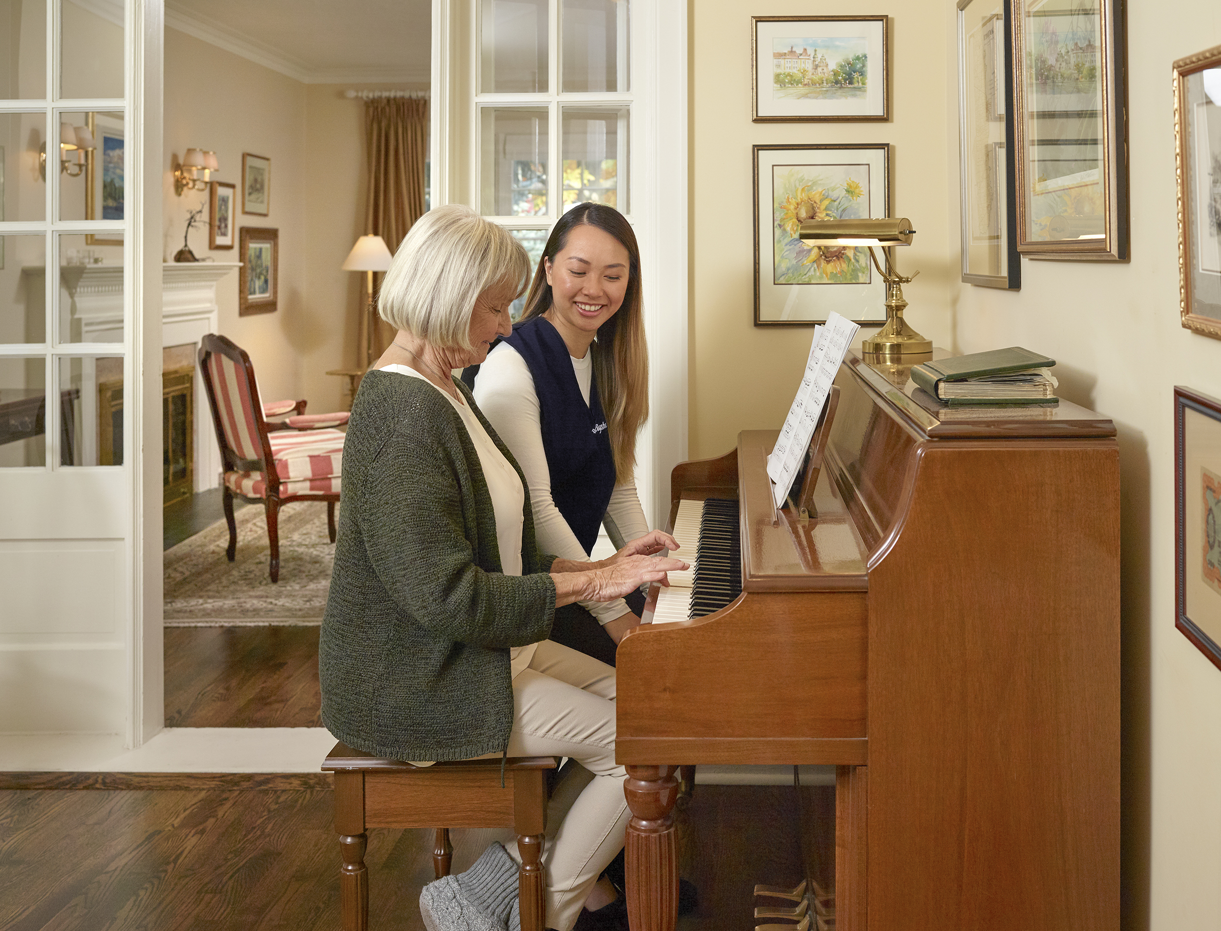 caregiver playing piano with senior woman