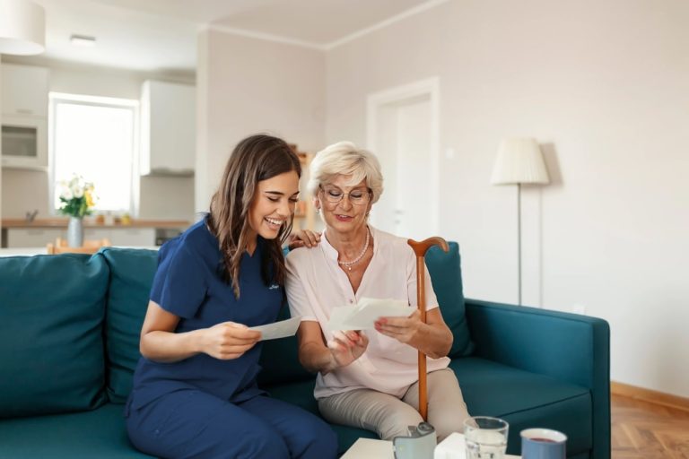 A nurse and an elderly woman sitting on a couch.