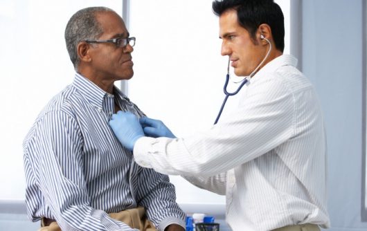 Doctor listening to man's heart