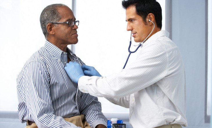 Doctor listening to man's heart