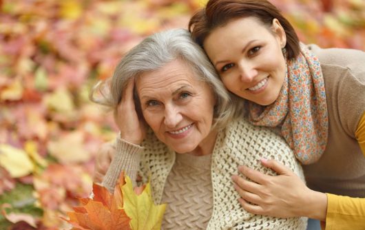 Jeune femme embrassant une femme âgée dans les feuilles d'automne