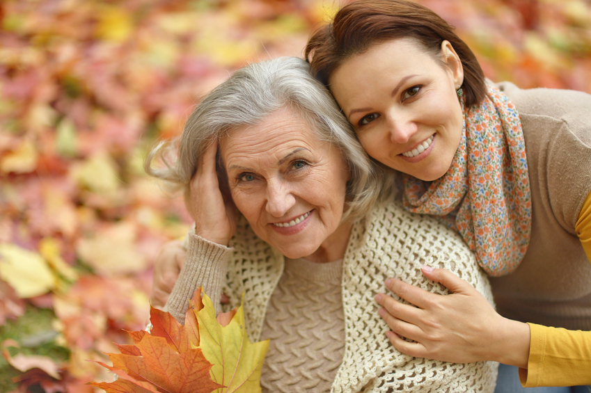 Jeune femme embrassant une femme âgée dans les feuilles d'automne