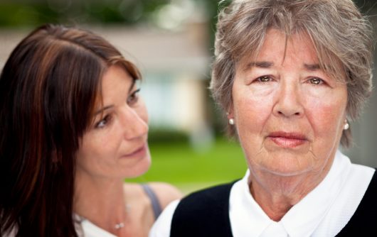 femme âgée regardant dans la caméra avec une femme adulte la regardant