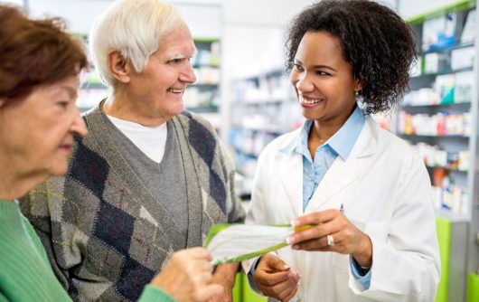 pharmacien donnant du papier à un couple de personnes âgées