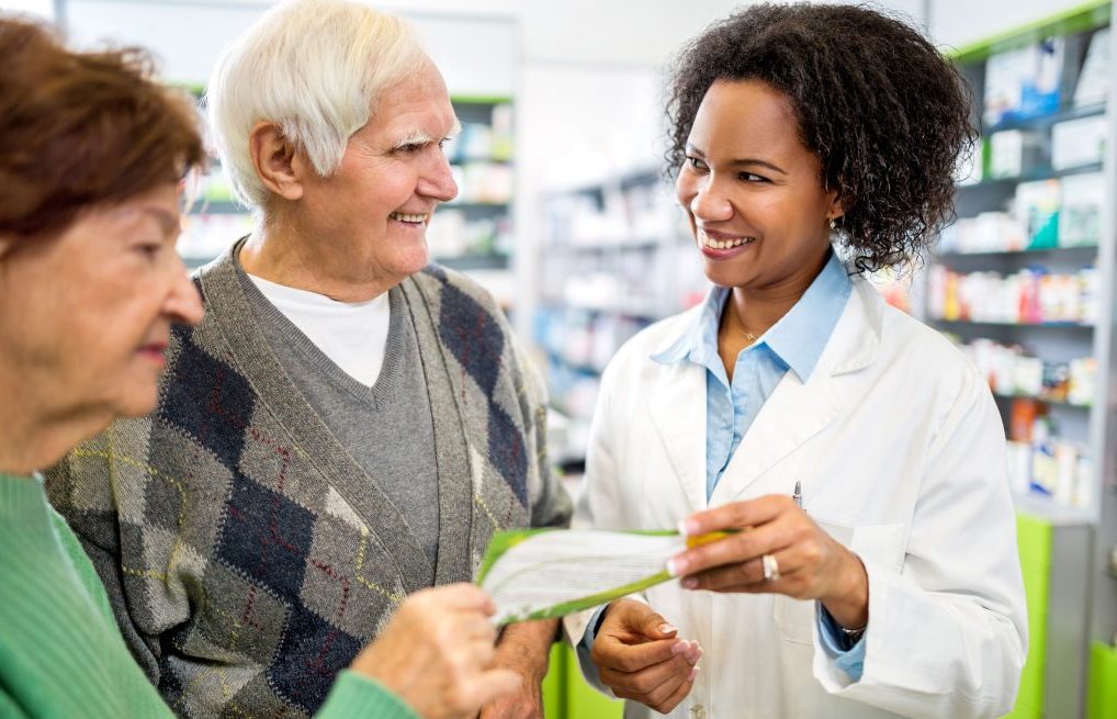 pharmacien donnant du papier à un couple de personnes âgées