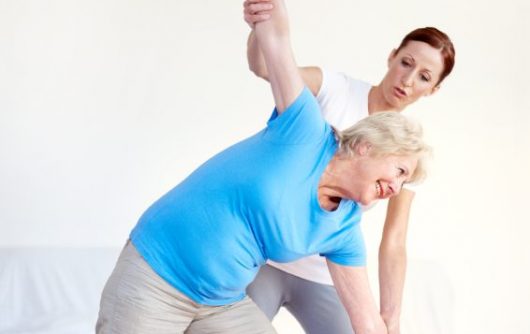 young woman helping elderly woman stretch