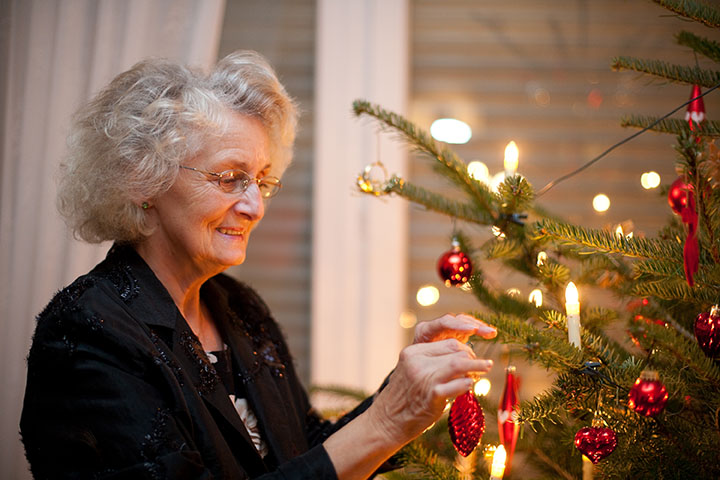 senior woman putting ornaments on tree
