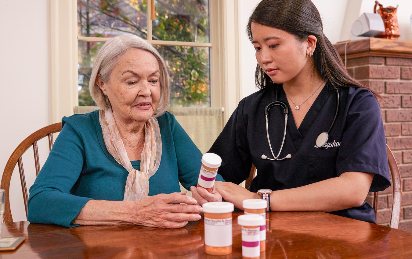 caregiver looking at medication with senior woman