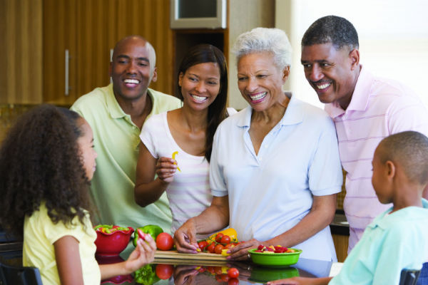 famille multigénérationnelle mangeant des légumes dans la cuisine et souriant