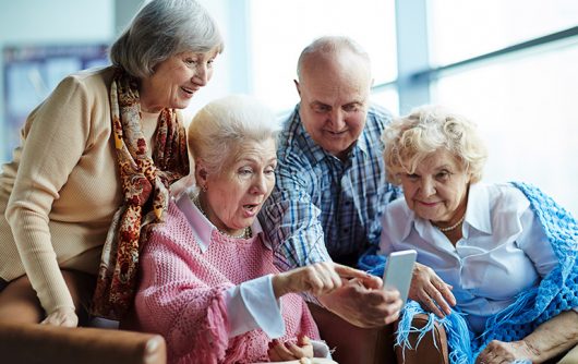 groupe de personnes âgées souriant au téléphone portable