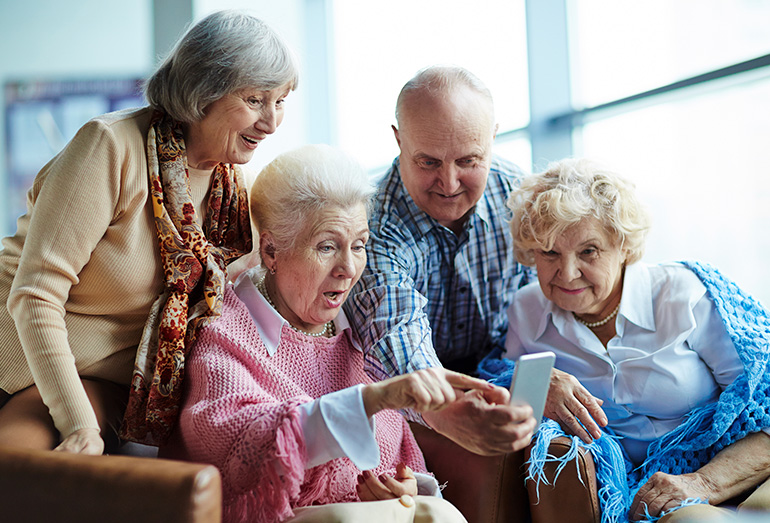 groupe de personnes âgées souriant au téléphone portable