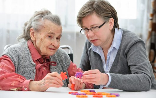 femme adulte aidant une femme âgée avec puzzle