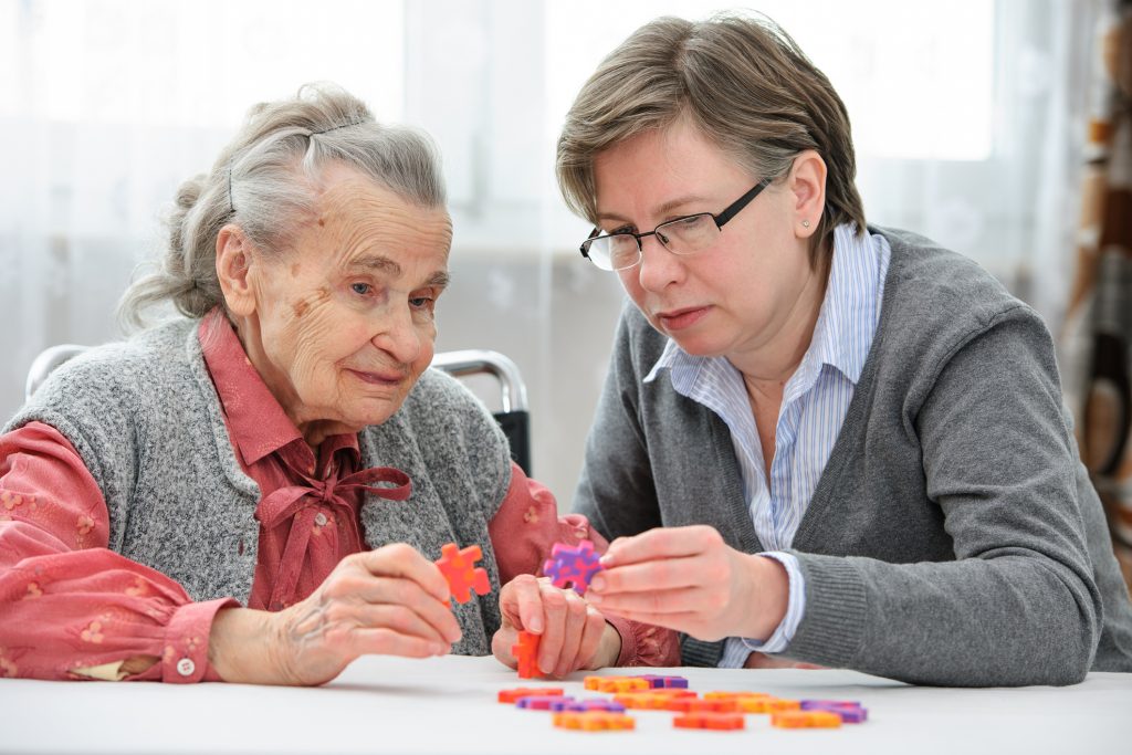 femme adulte aidant une femme âgée avec puzzle