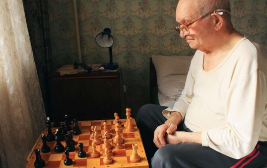 Senior man playing chess alone