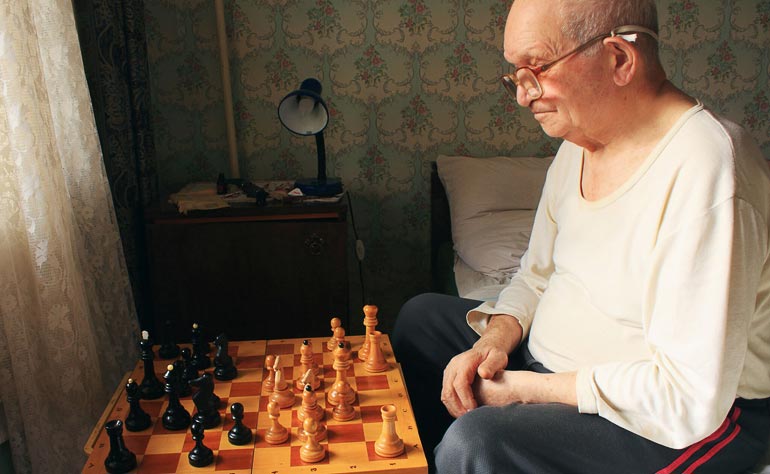 Senior man playing chess alone