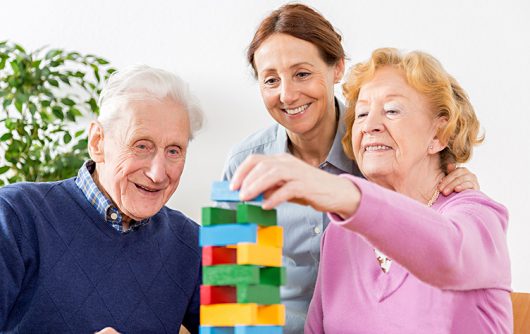 Caregiver playing jenga with senior couple