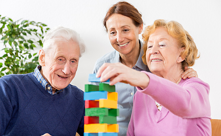 Caregiver playing jenga with senior couple