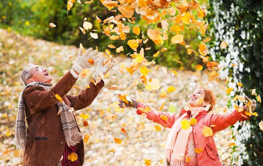 couple de personnes âgées jouant dans les feuilles d'automne