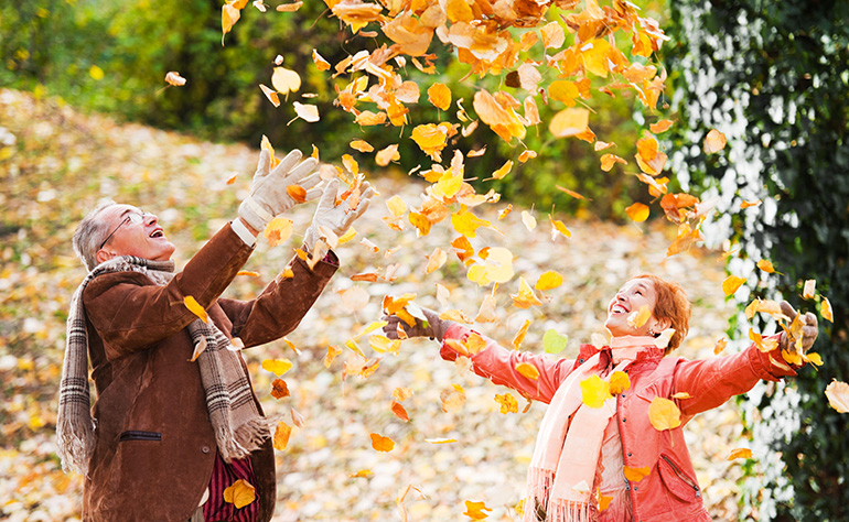couple de personnes âgées jouant dans les feuilles d'automne