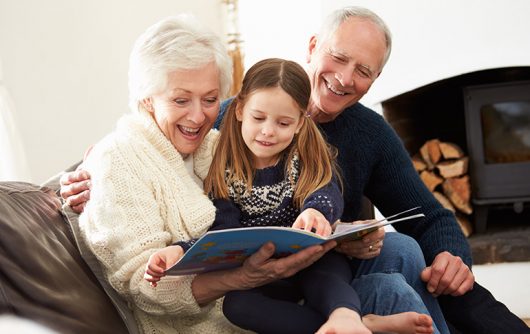 Senior couple reading book to young girl