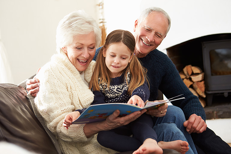 Senior couple reading book to young girl