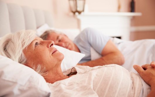 couples aînés, dans lit, femme regarde, plafond