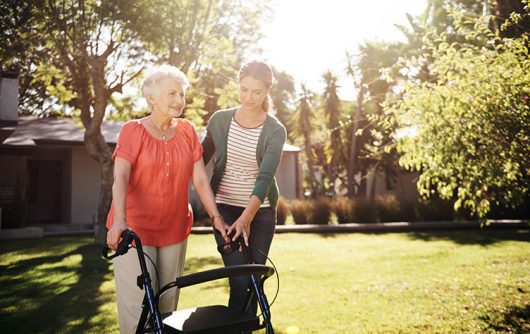 young woman helping senior woman with walker