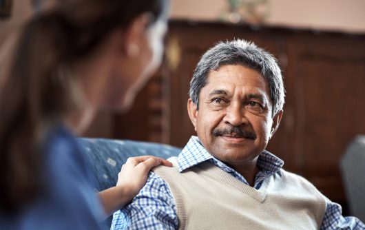 A caregiver sat with a senior man