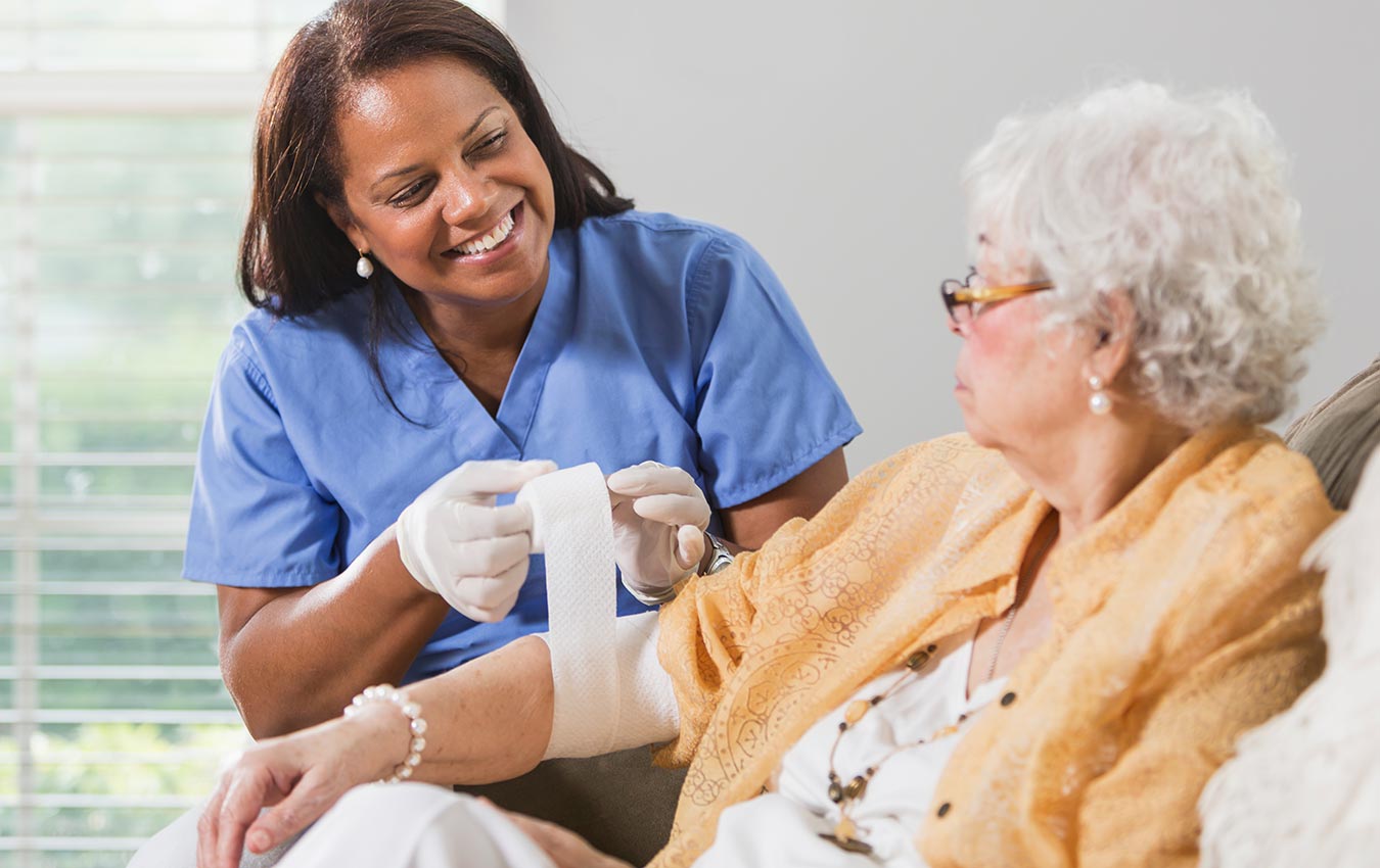 caregiver putting bandage on senior woman