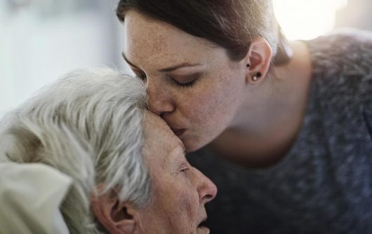 jeune femme embrassant une femme âgée sur le front