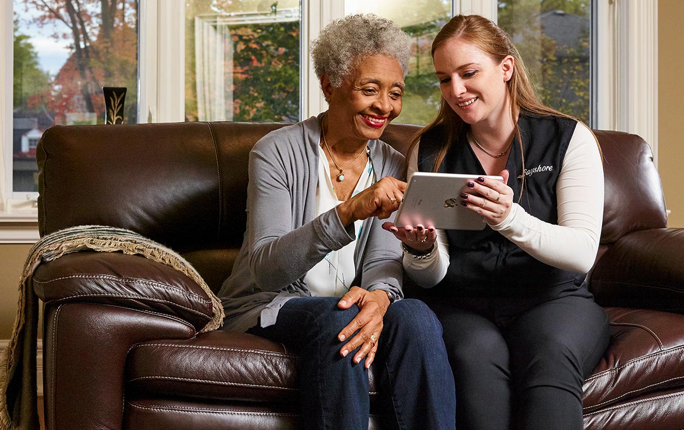 Caregiver helping senior woman on tablet