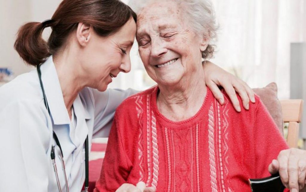 A doctor touching forehead with a patient while comforting her. It shows compassion and care.