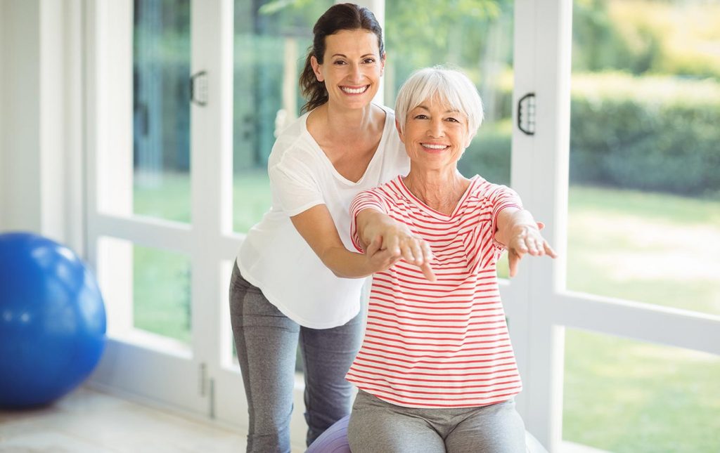 woman helping senior do yoga