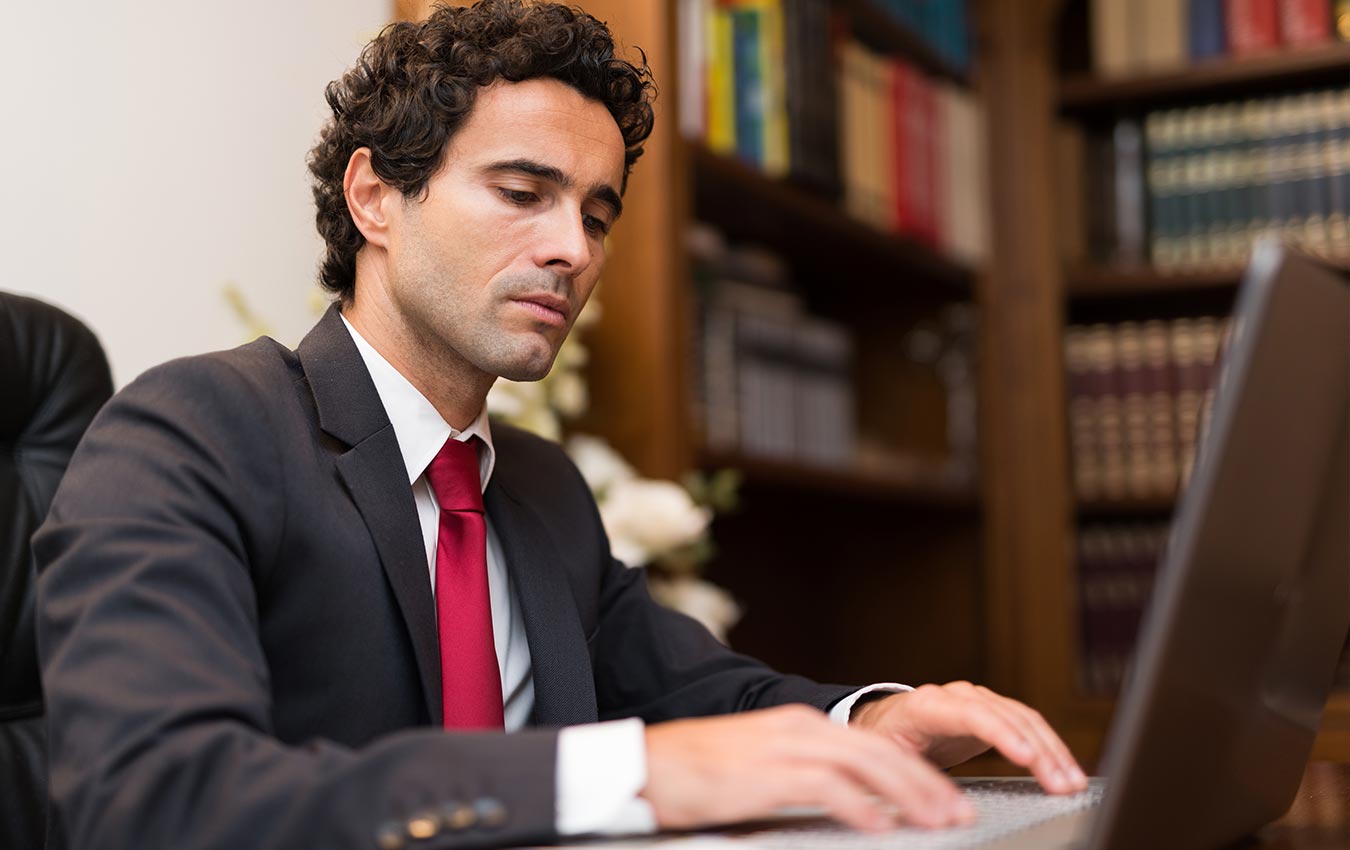 A man in a suit typing on his laptop.