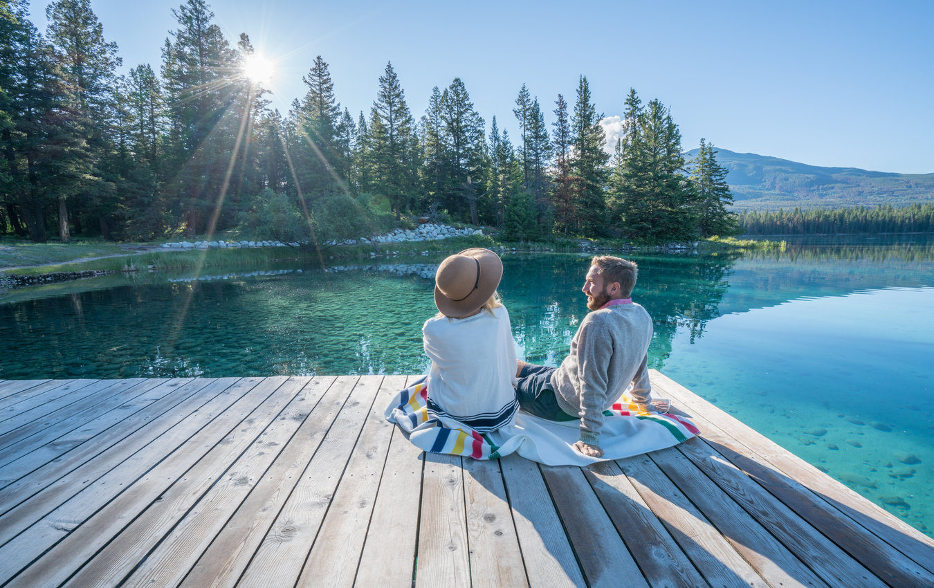 Couple sitting on dock in front of mountains