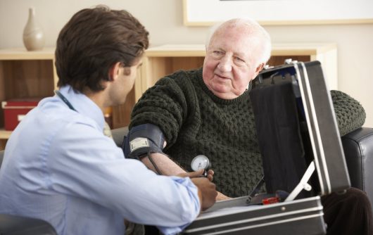 Physician taking senior man's blood pressure