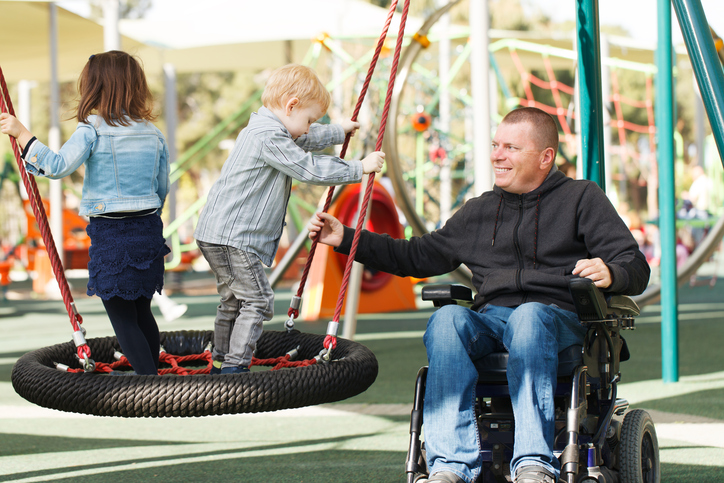 Man in wheelchair playing with kids are park