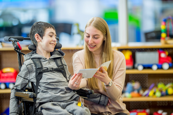 Woman reading to boy in wheelchair