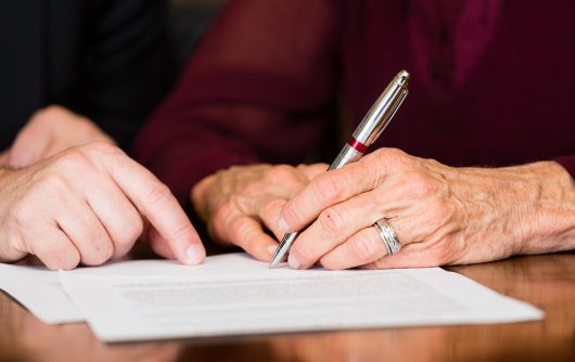 senior hands signing papers