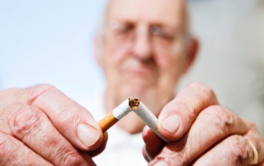 Senior man snapping cigarette in half