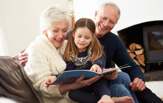 Grands-parents lisant à leur petite-fille