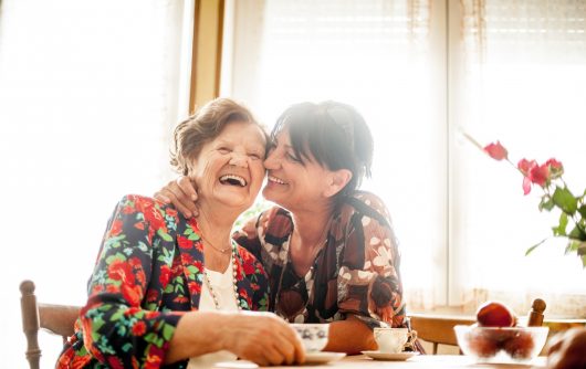 senior woman and daughter hugging at home