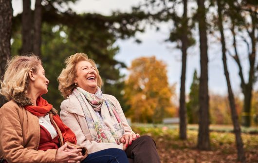 Two senior women laughing in park