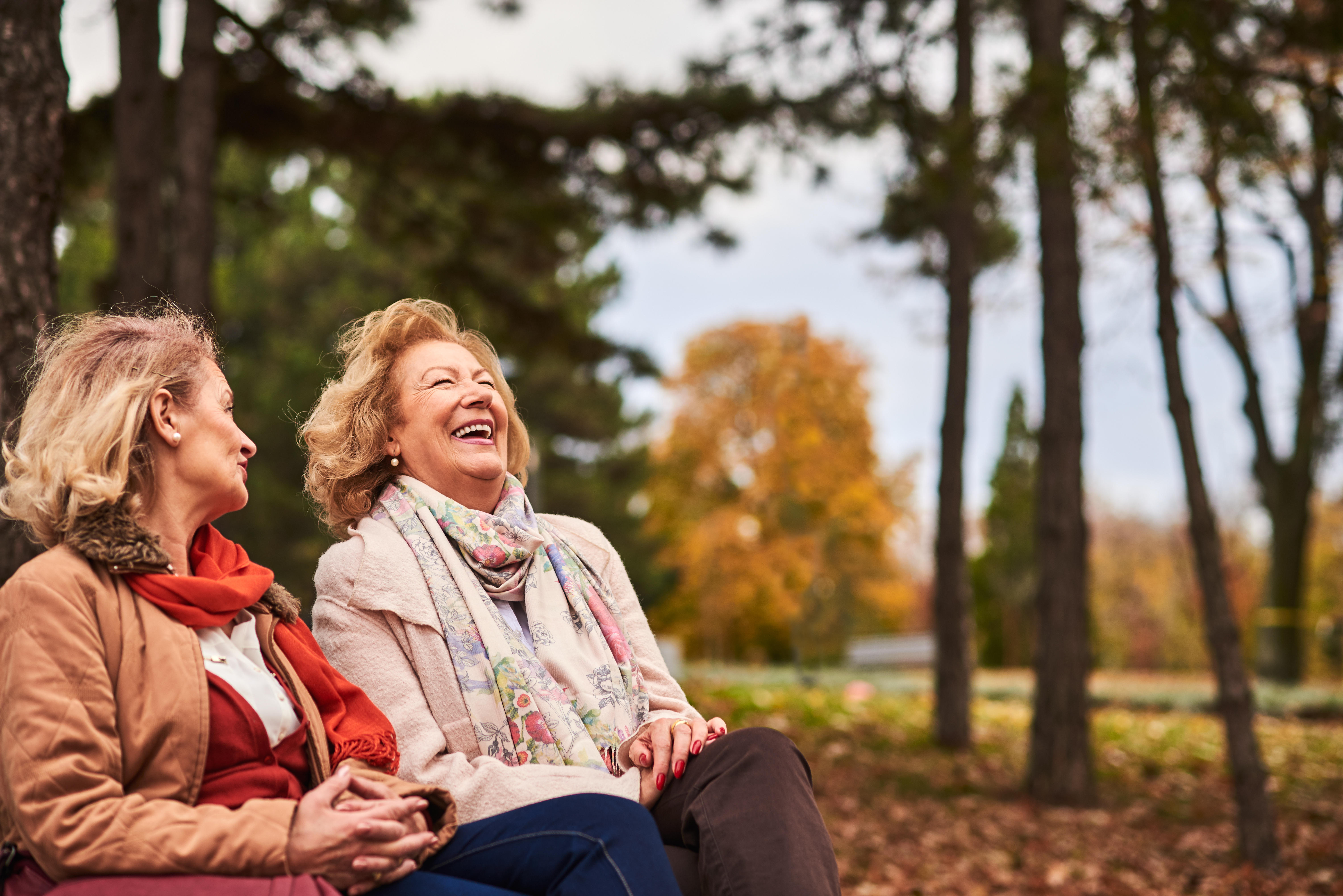 Two senior women laughing in park