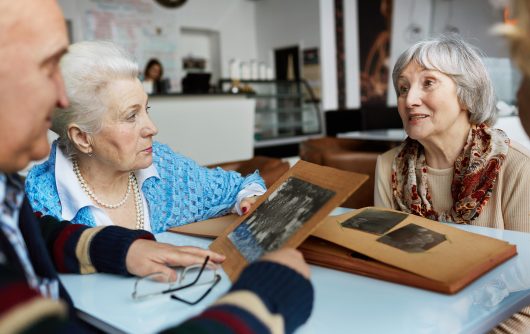 Friendly seniors talking while looking through photographs in a cafe