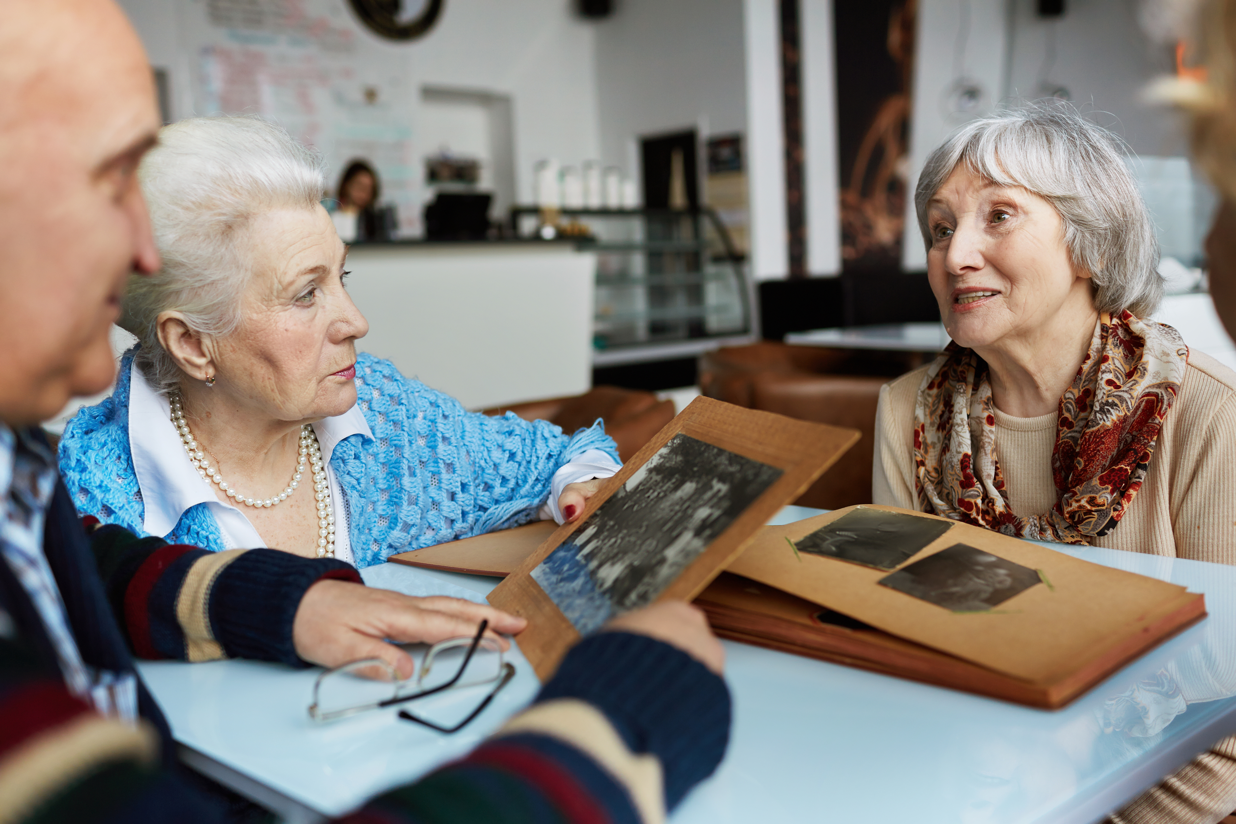 Friendly seniors talking while looking through photographs in a cafe