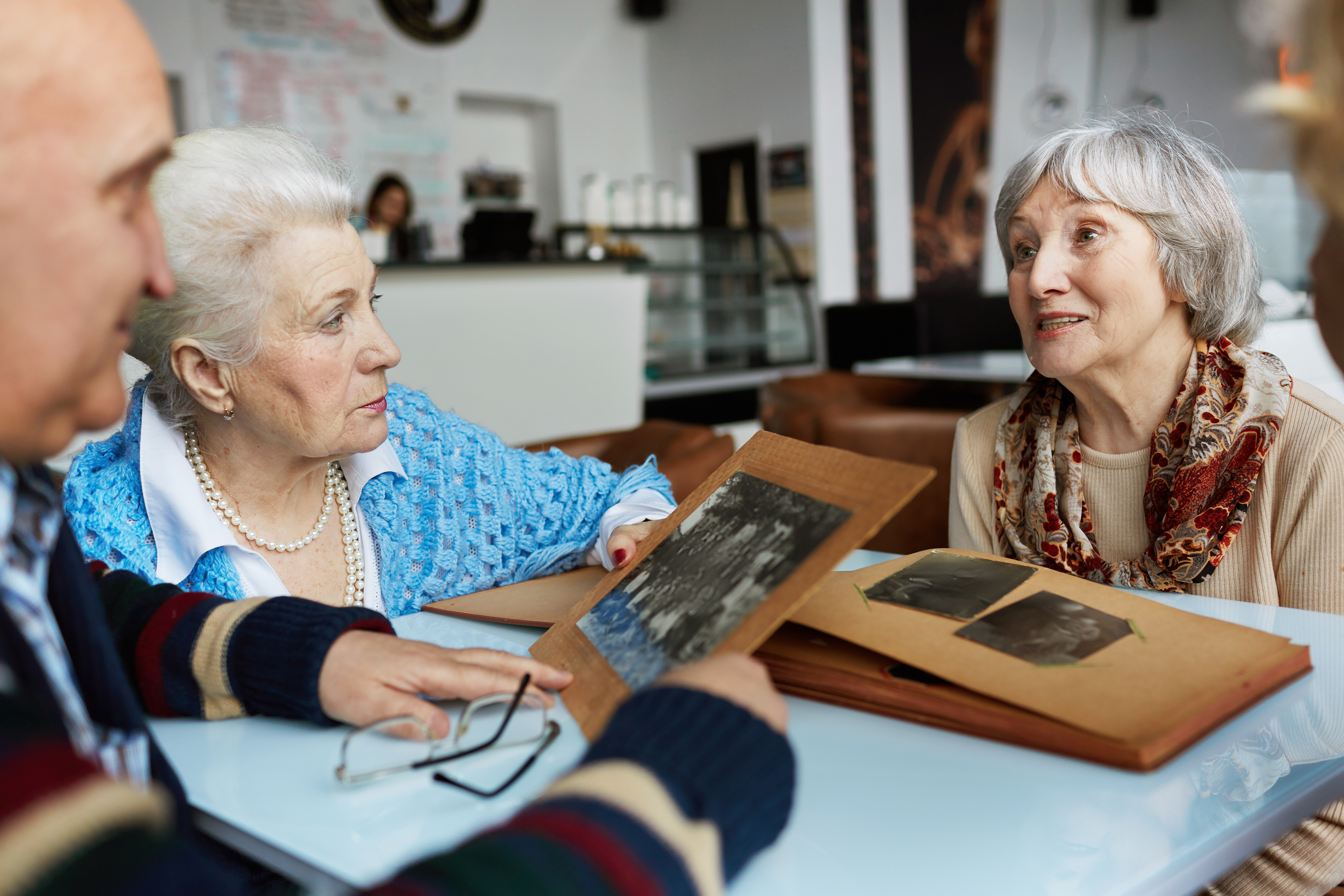 Aînés amicaux parlant tout en regardant à travers des photographies dans un café