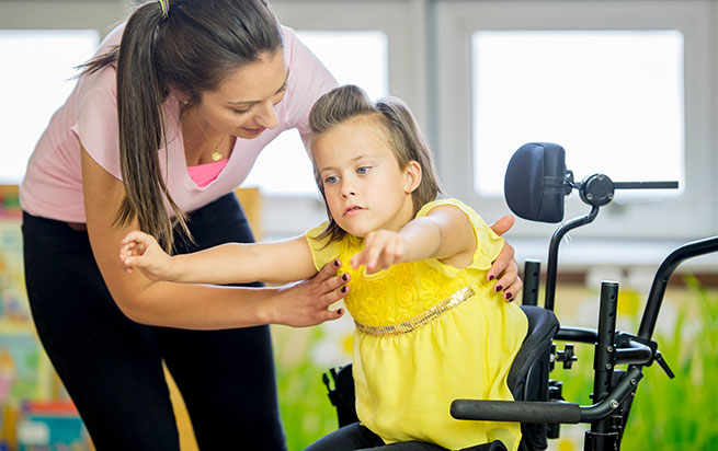 A female caregiver helping a girl get up from the walker.