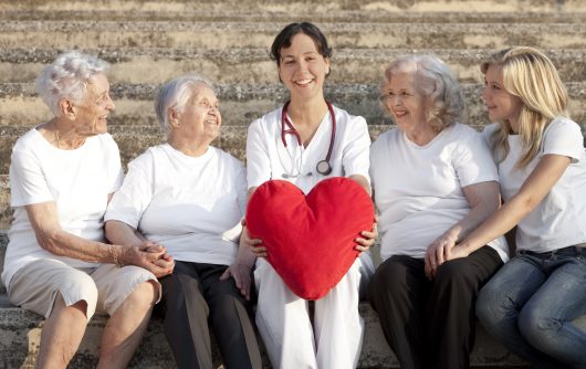 femme médecin avec un coussin cardiaque à la main avec trois femmes âgées et un petit-enfant, plus de personnes âgées